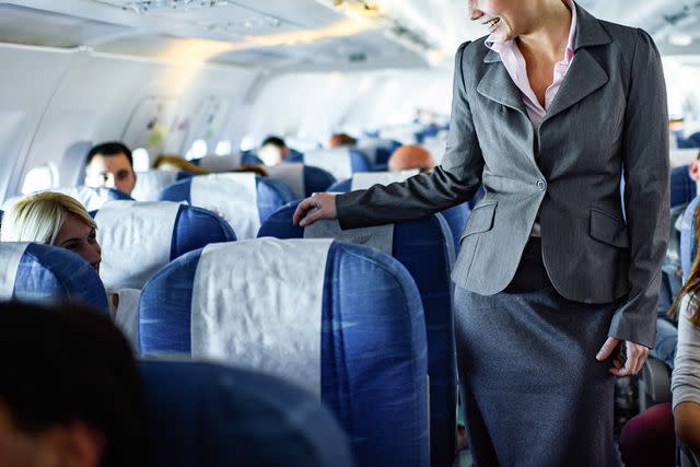 <p>BraunS/Getty</p> Flight attendant checking on passengers' seats.