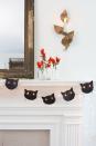 <p>Give your mantel the <em>purr-fect</em> makeover with this black cat garland made from black card stock and string lights. Use a set of spare Christmas lights for the glowing cat eyes, as shown.</p><p>To make this at home, start by downloading our <a href="http://clv.h-cdn.co/assets/cm/15/24/5578a73fa1435_-_Cat_silo.pdf" rel="nofollow noopener" target="_blank" data-ylk="slk:cat face template;elm:context_link;itc:0;sec:content-canvas" class="link ">cat face template</a><em>. </em>Using a white pencil, trace the template onto black card stock and cut out desired number of faces.</p><p>Give it some texture by fringing the sides of the cat's face and the top of its head with scissors. Then cut three pieces of black waxed twine, about 4" long for each cat and tie them together in the center of the twine, and glue to the cat's face as whiskers.</p><p>Finish this craft by using a standard single-hole punch to create holes for eyes toward the center of each cat's face. Hang string lights and position cat faces on 2 lightbulbs, one in each eye hole.</p>