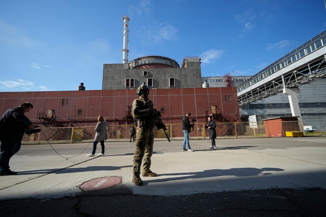 Foreign journalists work as a Russian soldier patrols an area at the Zaporizhzhia Nuclear Power Station, in Enerhodar, Zaporizhzhia region, in territory under Russian military control, southeastern Ukraine, on May 1, 2022.