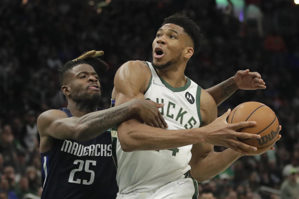 Milwaukee Bucks' Giannis Antetokounmpo is fouled by Dallas Mavericks' Reggie Bullock (25) during the second half of an NBA basketball game Sunday, April 3, 2022, in Milwaukee. (AP Photo/Aaron Gash)