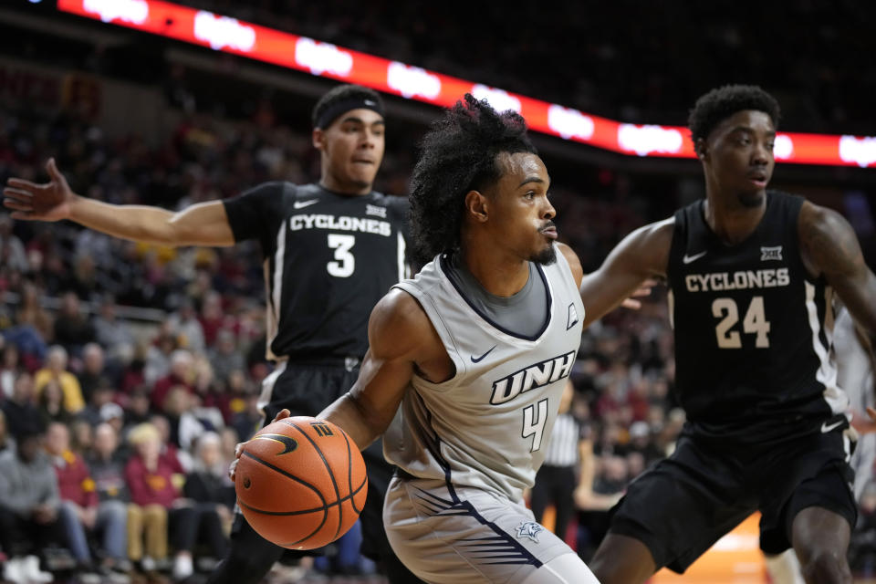 New Hampshire guard Ahmad Robinson (4) passes between Iowa State guard Tamin Lipsey (3) and forward Hason Ward (24) during the first half of an NCAA college basketball game, Sunday, Dec. 31, 2023, in Ames, Iowa. (AP Photo/Charlie Neibergall)