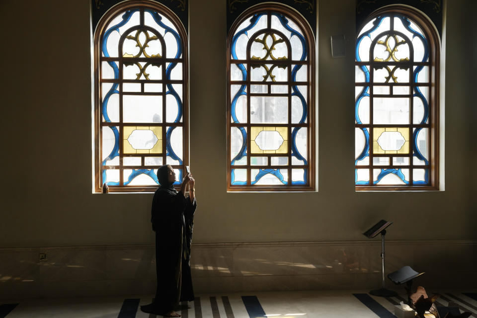 A Hungarian tourist, takes pictures at Katara mosque in Doha, Qatar, Tuesday, Dec. 6, 2022. Up to 1 million visitors have come to Qatar during the World Cup. For many it's their first visit to a Muslim country. Those who don't venture far beyond the stadiums and Doha's glitzy hotels will have only limited exposure to the country's religion, such as hearing the call to prayer at a distance or witnessing Muslims prostrate at prayer rooms in stadiums, airports and hotels. (AP Photo/Jorge Saenz)