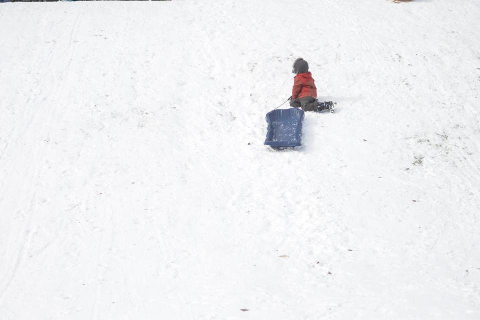 A boy rests halfway up the hill during an afternoon of sledding at Atkins Glen Park in Park Ridge, New Jersey, on Tuesday, Nov. 13, 2023.