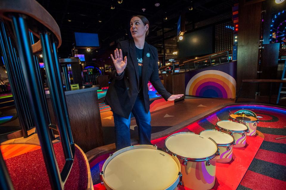 Suzie Dagenais, director of operations for Puttshack, shows off miniature golf hole featuring a drumline, Feb. 7, 2024. Puttshack opens to the public on Saturday.