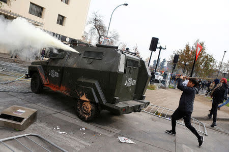 A demonstrator uses a stick against a riot police vehicle during an unauthorized march called by secondary students to protest against government education reforms in Santiago, Chile, May 26, 2016. REUTERS/Ivan Alvarado