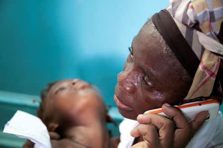 A woman holds a child suffering from yellow fever as she waits for a prescription at a hospital in Luanda?, Angola, March 15, 2016. REUTERS/Herculano Coroado