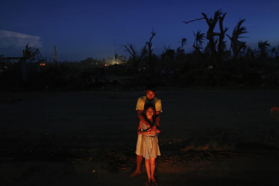 Relatives stand by candles lit on a mass grave by the side of a road south of Tacloban