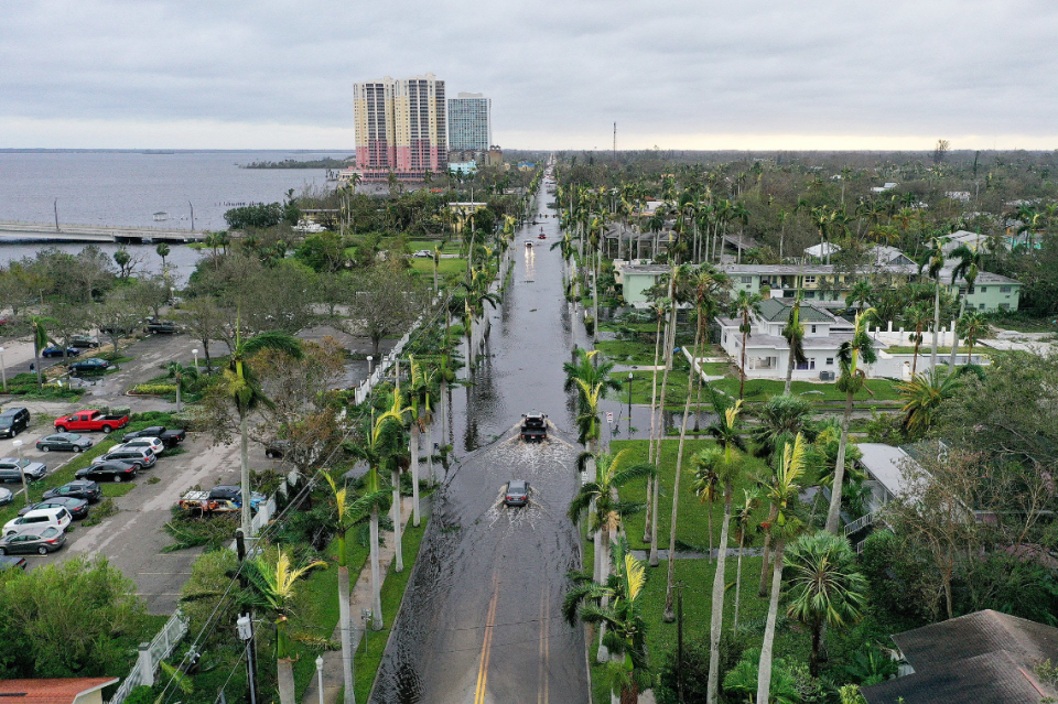 an aerial shot of florida's urban coastline, cars drive through a flooded road