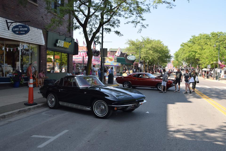 People look at a few cars during the car show at the Charlevoix Venetian Festival on July 21, 2023.