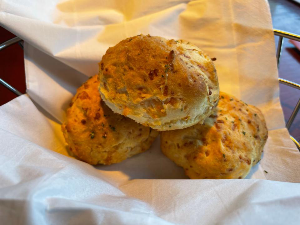 Three cheddar biscuits sit on a white napkin inside of a metal basket at Red Lobster