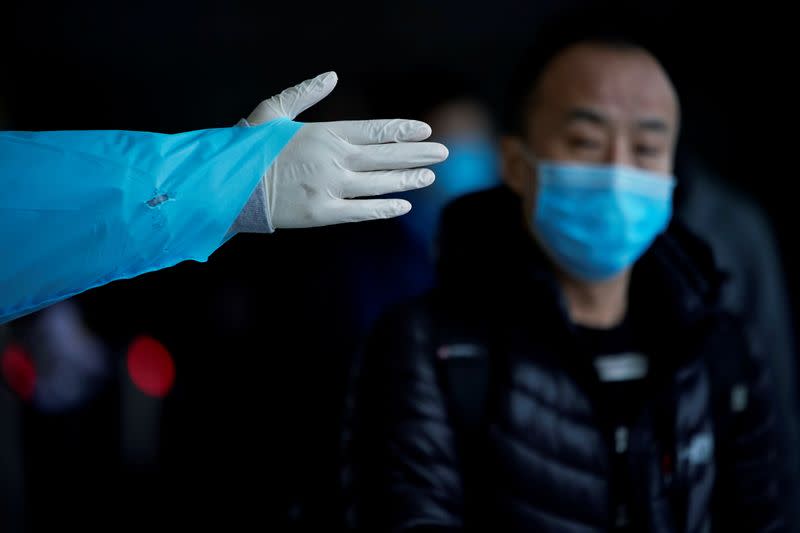 A passenger wearing a mask walks outside the Shanghai railway station in Shanghai