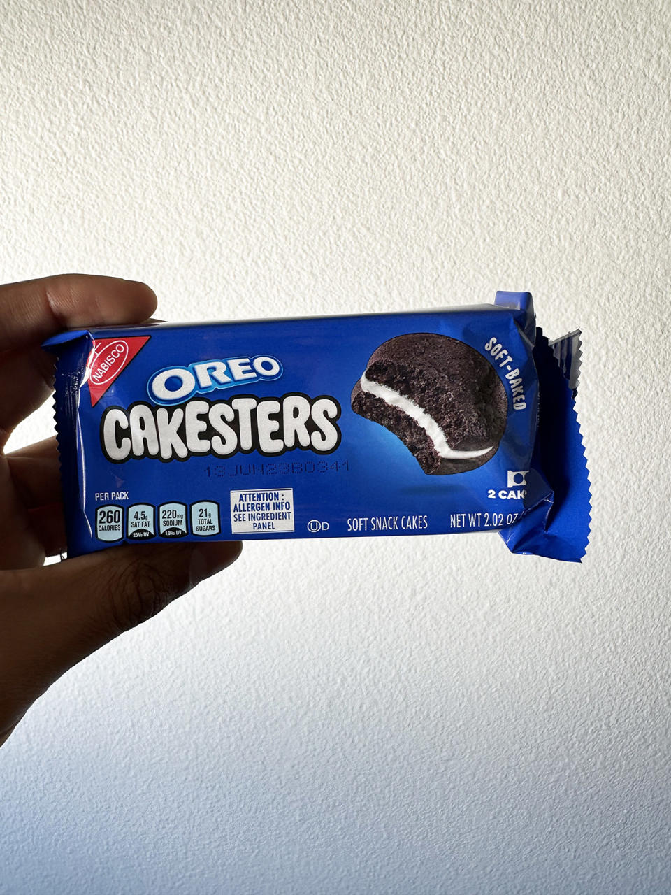 A hand holding a small pack of Oreo Cakesters