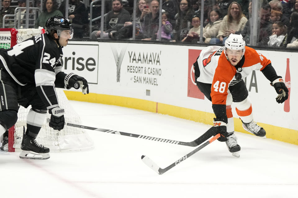 Los Angeles Kings center Phillip Danault, left, and Philadelphia Flyers center Morgan Frost reach for the puck as it bounces in front of the face of Frost during the first period of an NHL hockey game Saturday, Nov. 11, 2023, in Los Angeles. (AP Photo/Mark J. Terrill)