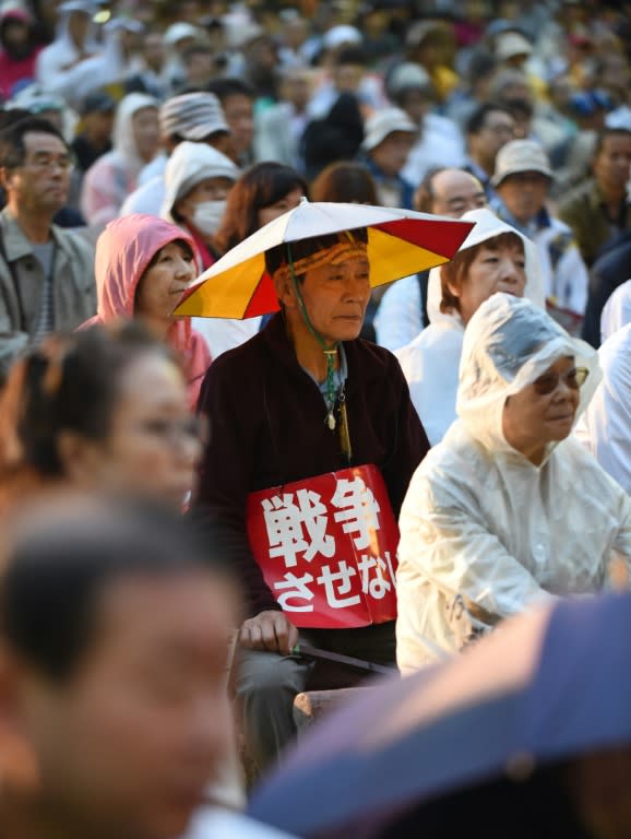 A man listens to a speech as he holds a banner reading "No War", during a rally in Tokyo on August 26, 2015 organized by lawyers against controversial security bills which would expand the remit of the country's armed forces