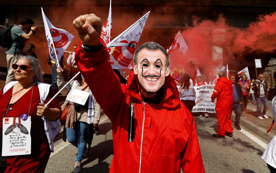 A protester wears a mask depicting Emmanuel Macron at a demonstration in Nice on Thursday - Eric Gaillard/Reuters