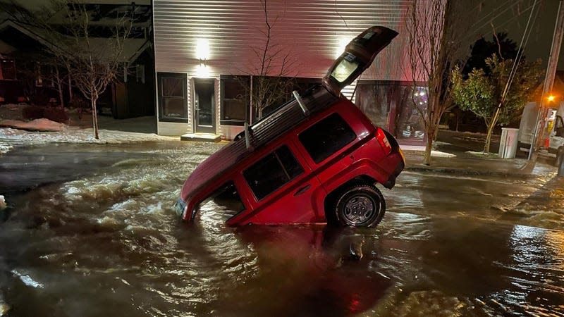A red 2015 Jeep Patriot in a sinkhole.