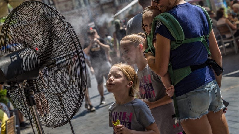 Girl stands in front of misting fan outside