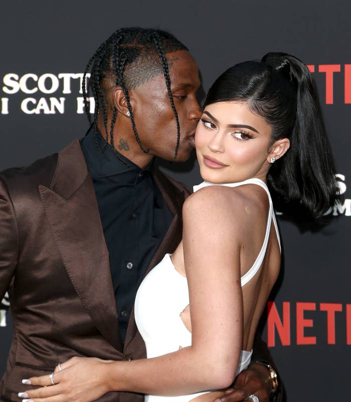 The couple cuddling at the stand in on a red carpet in front of photographers