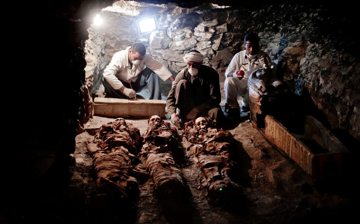 Archaeologists work on mummies found in the New Kingdom tomb that belongs to a royal goldsmith in Luxor - AP