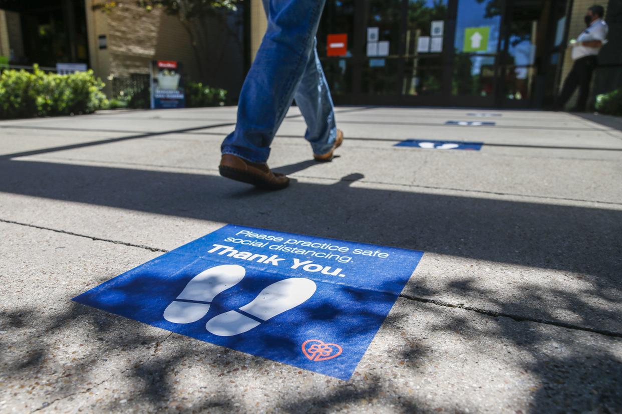 A shopper passes by social distancing markers as they enter NorthPark Center mall on Friday, May 1, 2020, in Dallas, Texas. Texas Gov. Greg Abbott's executive order requiring Texans to stay at home expired on the day before, allowing businesses to reopen under certain conditions as soon as Friday. Stores, restaurants and movie theaters may open as long as they maintain only a 25 percent occupancy and follow social distancing. Under those guidelines, malls can also open but food courts, play areas and interactive displays or settings must remain closed.