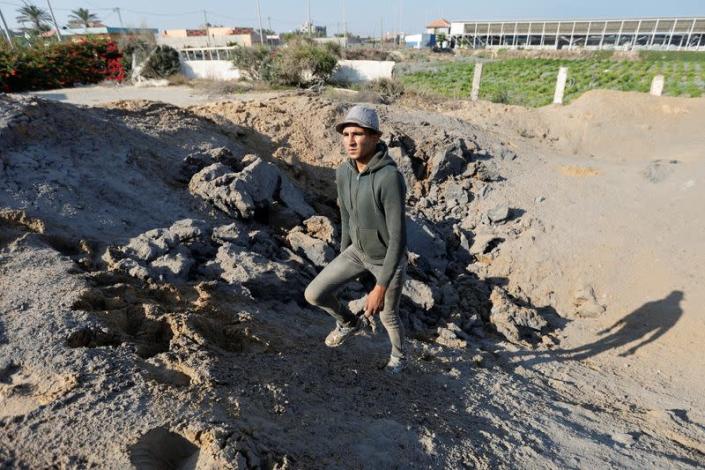 Palestinian man stands at the site of an Israeli air strike carried out in Gaza
