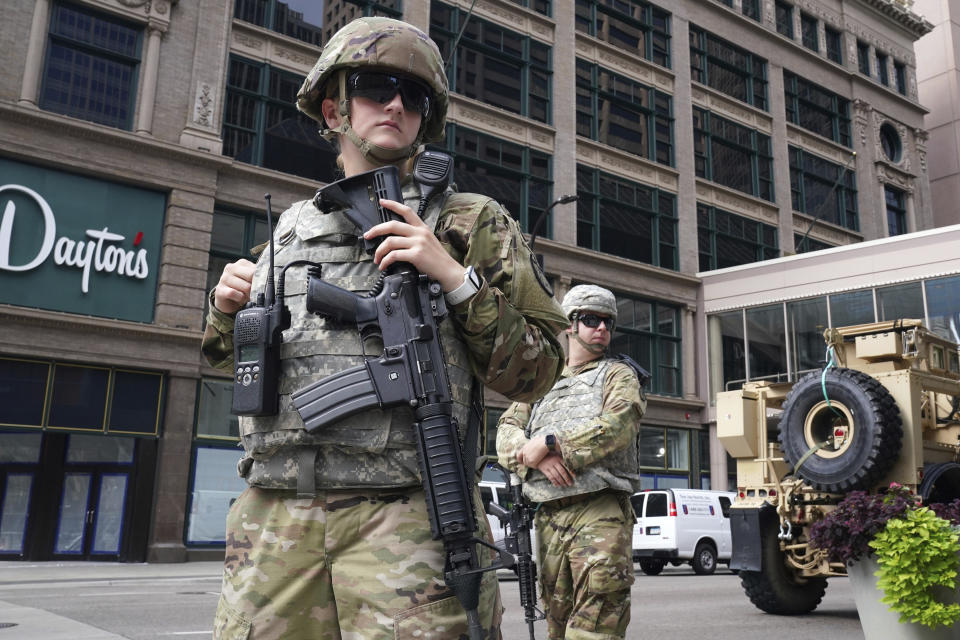 Members of the Minnesota National Guard stand at the intersection of South 7th Street and Nicollet Mall, Thursday, Aug. 27, 2020, in Minneapolis, as community members and business owners cleaned up the damaged that was caused by a group of looters Wednesday night after the suicide of a homicide suspect on the Mall ignited rioting. (Anthony Souffle/Star Tribune via AP)