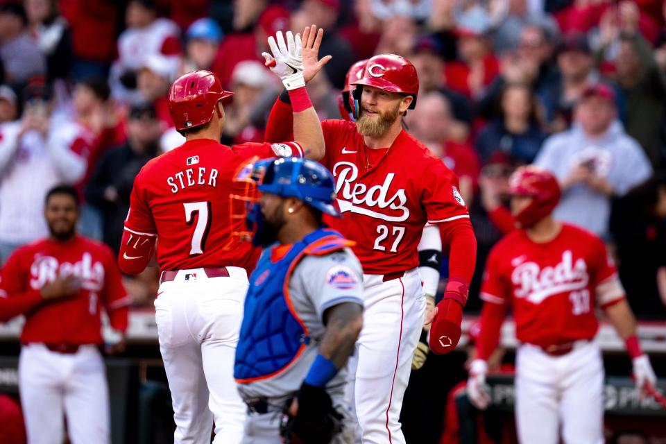 Cincinnati Reds outfielder Spencer Steer (7) high fives Cincinnati Reds outfielder Jake Fraley (27) after hitting a 3-run home run in the eighth inning of the MLB baseball game between the Cincinnati Reds and New York Mets at Great American Ball Park in Cincinnati on Saturday, April 6, 2024.