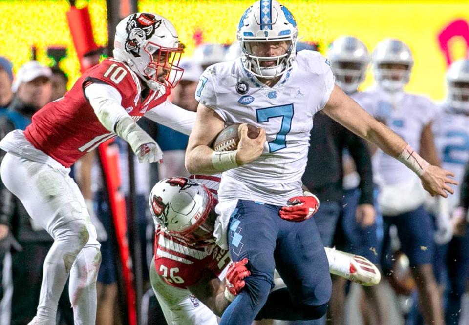 N.C. State’s Devon Betty (26) stops North Carolina quarterback Sam Howell (7) after a 24-yard gain in the fourth quarter on Friday, November 26, 2021 at Carter-Finley Stadium in Raleigh, N.C.