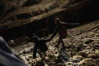 Migrants walk towards the border fence under surveillance of U.S. Border patrols as they attempt to get into the U.S. side to San Diego, Calif., from Tijuana, Mexico, Tuesday, Jan. 1, 2019. Discouraged by the long wait to apply for asylum through official ports of entry, many migrants from recent caravans are choosing to cross the U.S. border wall and hand themselves in to border patrol agents. (AP Photo/Daniel Ochoa de Olza)