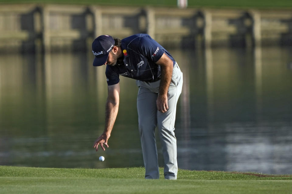 Max Homa takes a drop after hitting into the water on the 18th hole during the first round of The Players Championship golf tournament Thursday, March 14, 2024, in Ponte Vedra Beach, Fla. (AP Photo/Lynne Sladky)