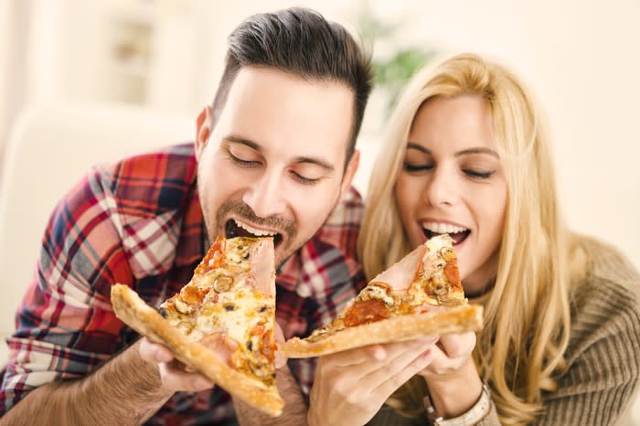 A couple eating pizza.