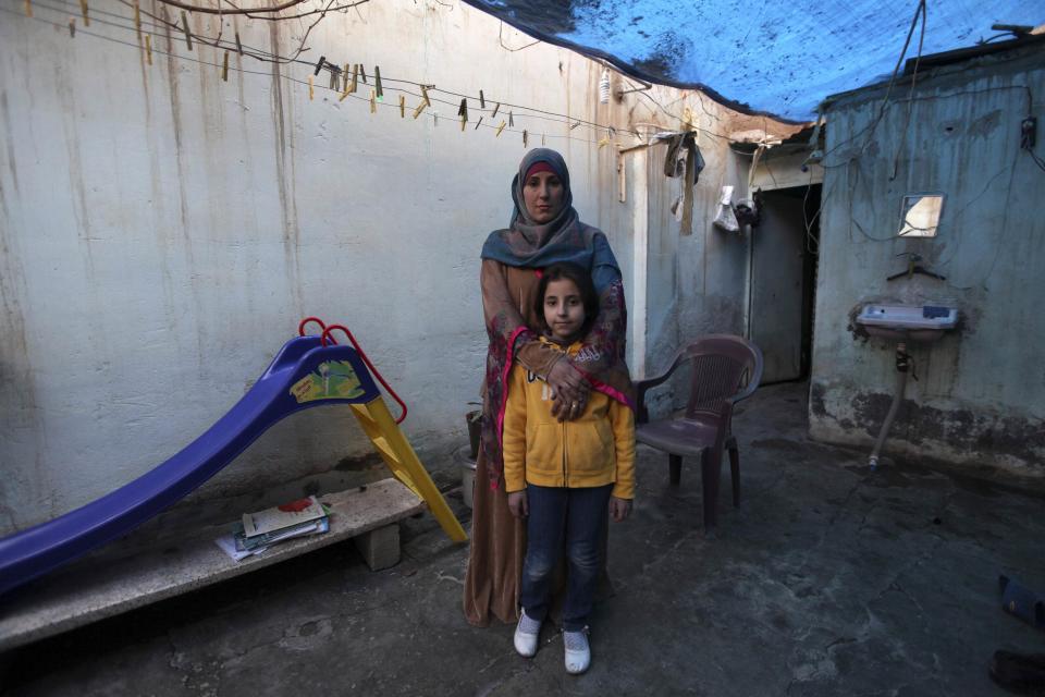 Bidaa Mhem Thabet al-Hasan poses with her daughter Mariam Khaled Masto outside their home in Deir al-Zor