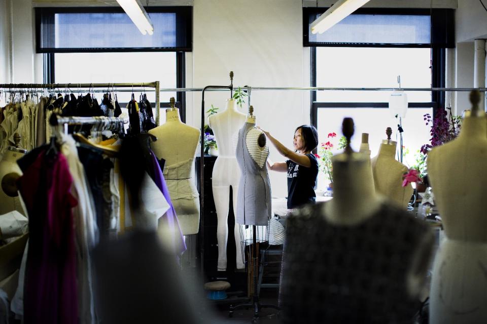 In this Aug 30, 2013 photo, designer Annie Le handles a dress on a mannequin in the production room of the New York studio of fashion designer Carmen Marc Valvo. Valvo will show his Spring 2014 collection on Sept. 6 at Lincoln Center in New York. (AP Photo/John Minchillo)