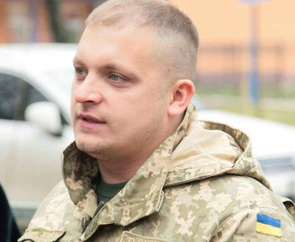 Artem Semenikhin wears a camouflage jacket with a Ukrainian flag on the sleeve.