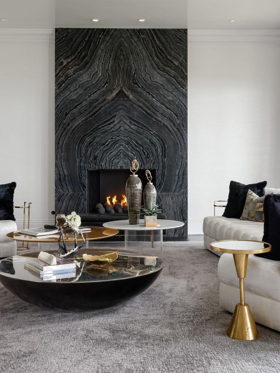 a fireplace in a room with a marbled surround that matches the space's cocktail tables