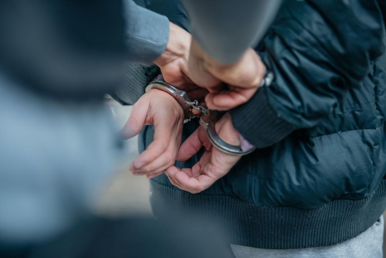 Policeman unlocking a handcuffs on the criminal's back.