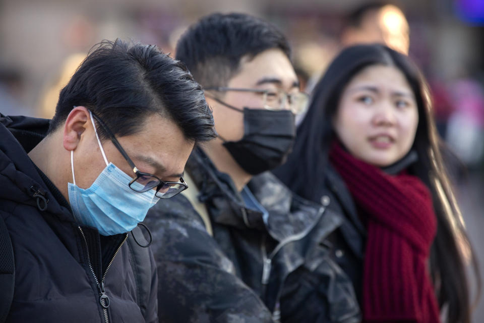 Travelers wear face masks as they walk outside of the Beijing Railway Station in Beijing, Monday, Jan. 20, 2020. China reported Monday a sharp rise in the number of people infected with a new coronavirus, including the first cases in the capital. The outbreak coincides with the country's busiest travel period, as millions board trains and planes for the Lunar New Year holidays. (AP Photo/Mark Schiefelbein)