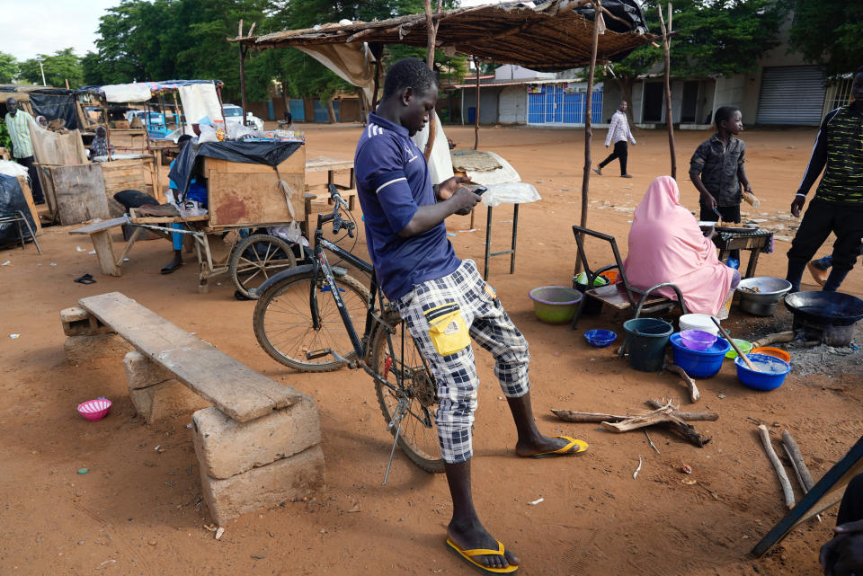 A man checks his phone in Niamey, Niger, Friday, Aug. 11, 2023. The ECOWAS bloc said it had directed a "standby force" to restore constitutional order in Niger after its deadline to reinstate ousted President Mohamed Bazoum expired. (AP Photo/Sam Mednick)