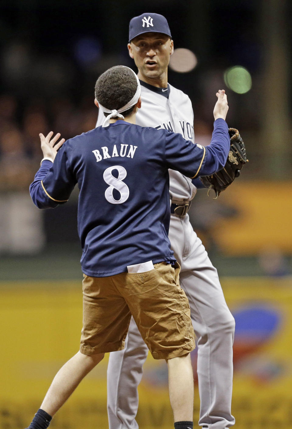 A fan runs out on the field to New York Yankees' Derek Jeter in the sixth inning of a baseball game against the Milwaukee Brewers, Friday, May 9, 2014, in Milwaukee. (AP Photo/Jeffrey Phelps)