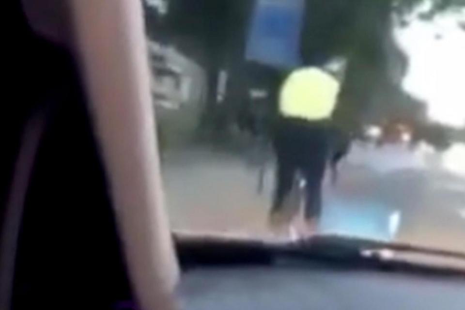 A still image from the video footage shows a car approaching the cyclist