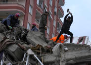 Emergency team members and others search for people in a destroyed building in Adana, Turkey, Monday, Feb. 6, 2023. A powerful earthquake has knocked down multiple buildings in southeast Turkey and Syria and many casualties are feared. (AP Photo/Khalil Hamra)