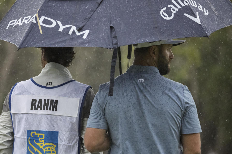 Jon Rahm, right, of Spain, and his caddie wait for his turn to putt on the sixth green during the first round of the RBC Heritage golf tournament, Thursday, April 13, 2023, in Hilton Head Island, S.C. (AP Photo/Stephen B. Morton)