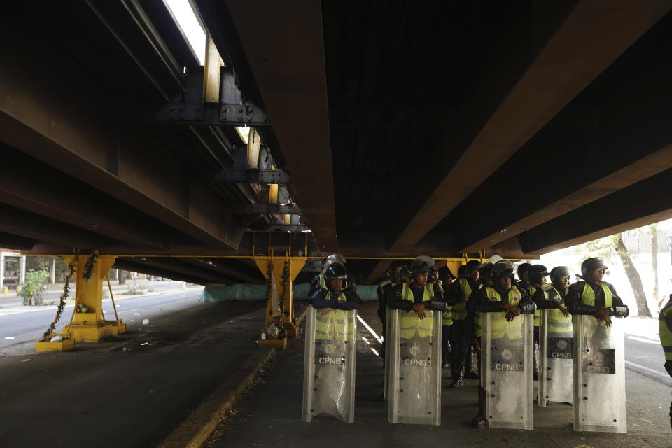 National Bolivarian Police take their turn to get out of the sun, under a road bridge, as their group patrols the sidelines of a pro-government march marking the anniversary of the 1958 coup that overthrew dictator Marcos Perez Jimenez in Caracas, Venezuela, Tuesday, Jan. 23, 2024. (AP Photo/Jesus Vargas)