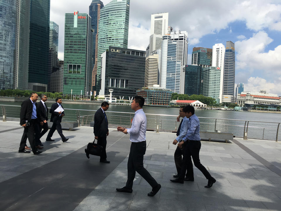 Businessmen walk along the Marina Bay financial district of Singapore on Thursday, Jan. 14, 2016. Singapore, which is about the size of New York City, has a population of more than 5 million and its economy relies mainly on finance, tourism and manufacturing. (AP Photo/Wong Maye-E)