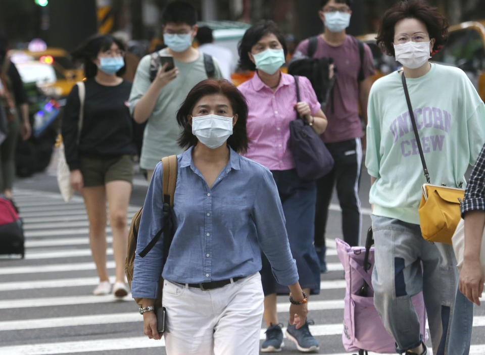 People wearing face masks to protect against the spread of the coronavirus cross and intersection in Taipei, Taiwan, Friday, Nov. 20, 2020. (AP Photo/Chiang Ying-ying)