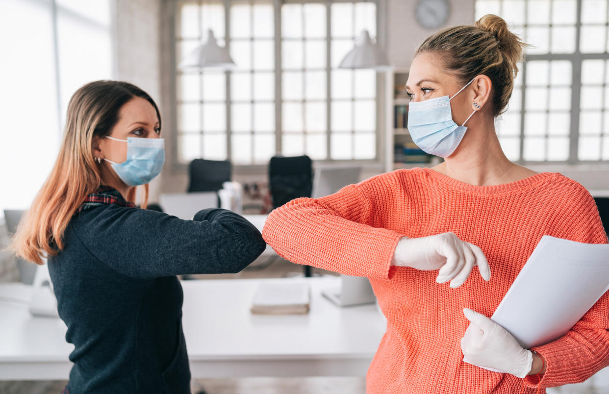 Colleagues in the office practicing alternative greeting for safety and protection during COVID-19