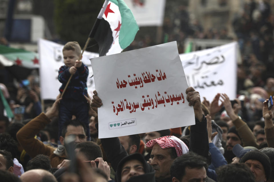 An anti-Syrian government protester holds up an Arabic placard that reads: "Hafez died and Hama stayed and Bashar will die and Syria will stay free," to mark 10 years since the start of a popular uprising against President Bashar Assad's rule, that later turned into an insurgency and civil war, In Idlib, the last major opposition-held area of the country, in northwest Syria, Monday, March 15, 2021. (AP Photo/Ghaith Alsayed)