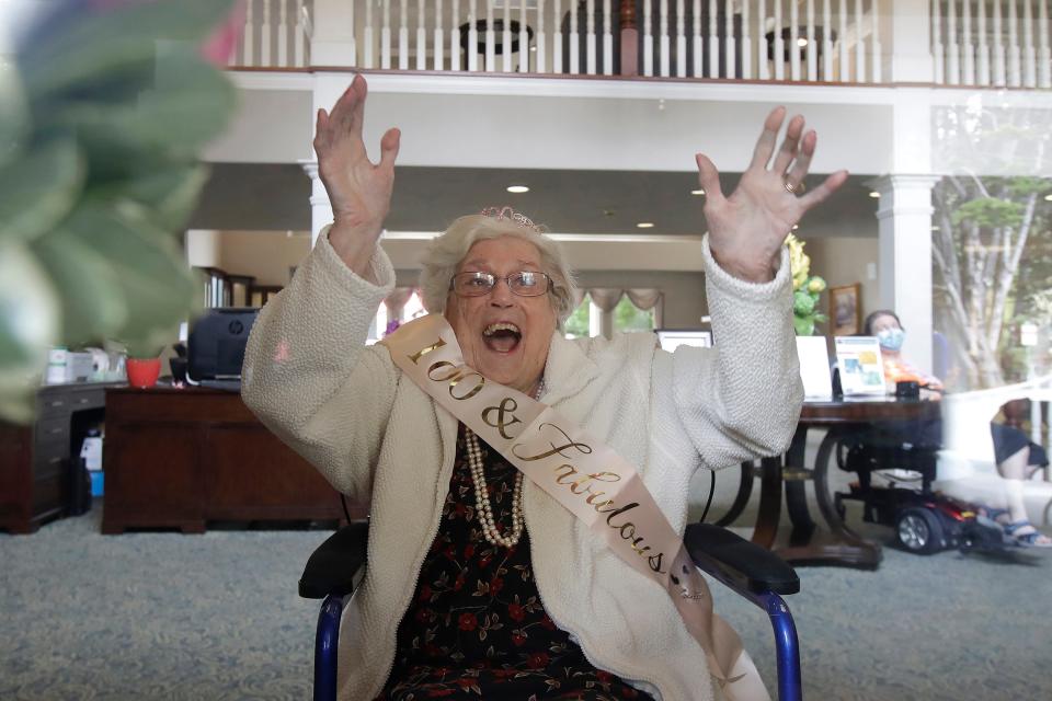 Rhoda Kay waves to family members while celebrating her 100th birthday from behind a window at Aegis Living San Francisco, as no visitors are allowed inside the the senior living facility during the coronavirus outbreak, in South San Francisco, Calif., Saturday, May 9, 2020.\