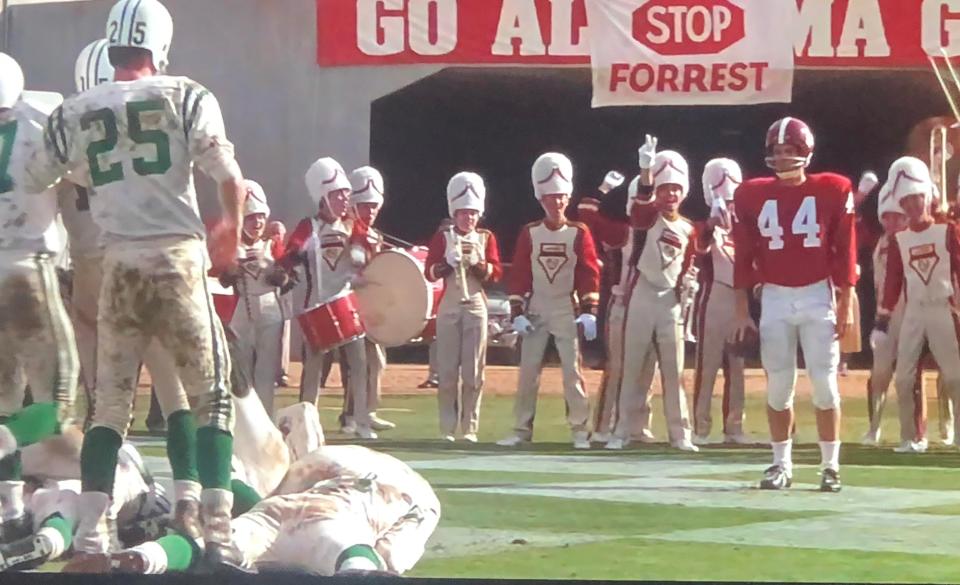 Forrest in a clean uniform and surrounded by football players in dirty uniforms