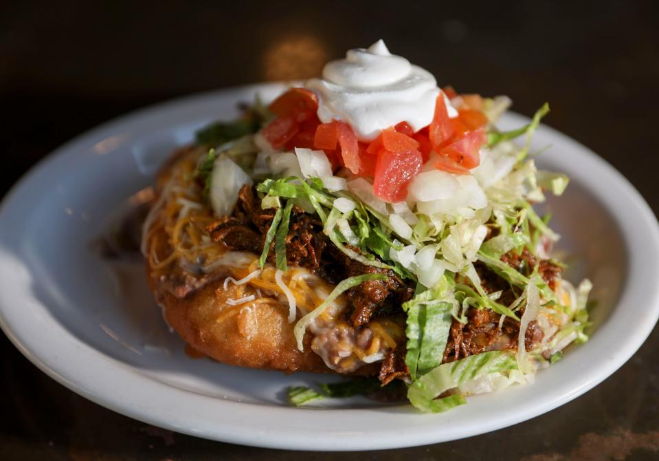 A fry bread taco topped with pork, refried beans, cheese, lettuce, tomato and sour cream is served at the Night Deposit Whiskey Library in Salem, Ore.